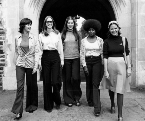 Five women walking through an archway on the Duke University campus.