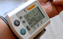 Digital blood pressure monitor worn on a person's wrist.