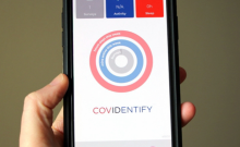 Closeup of adult hand holding smartphone showing screenshot of Covidentify app