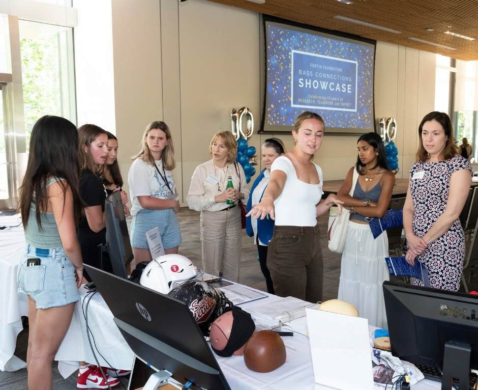 Student shows DASHR earpiece to attendees at showcase.