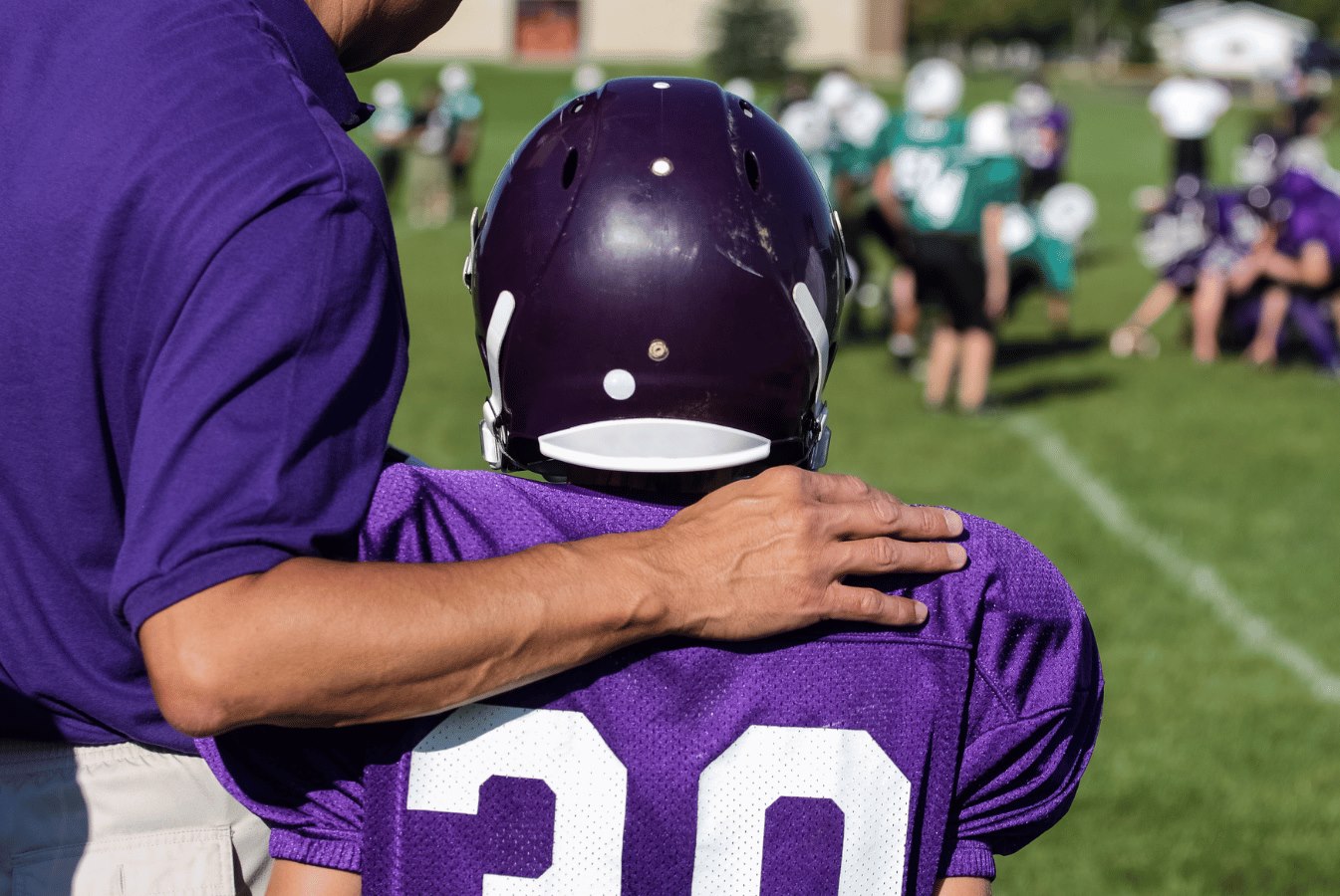 Coach and youth football player view the field.