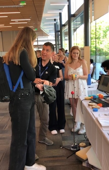 Jason Luck shows the DASHR earpiece to an attendee at showcase.