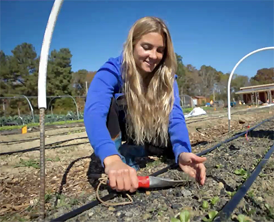 Student with spade at farm.