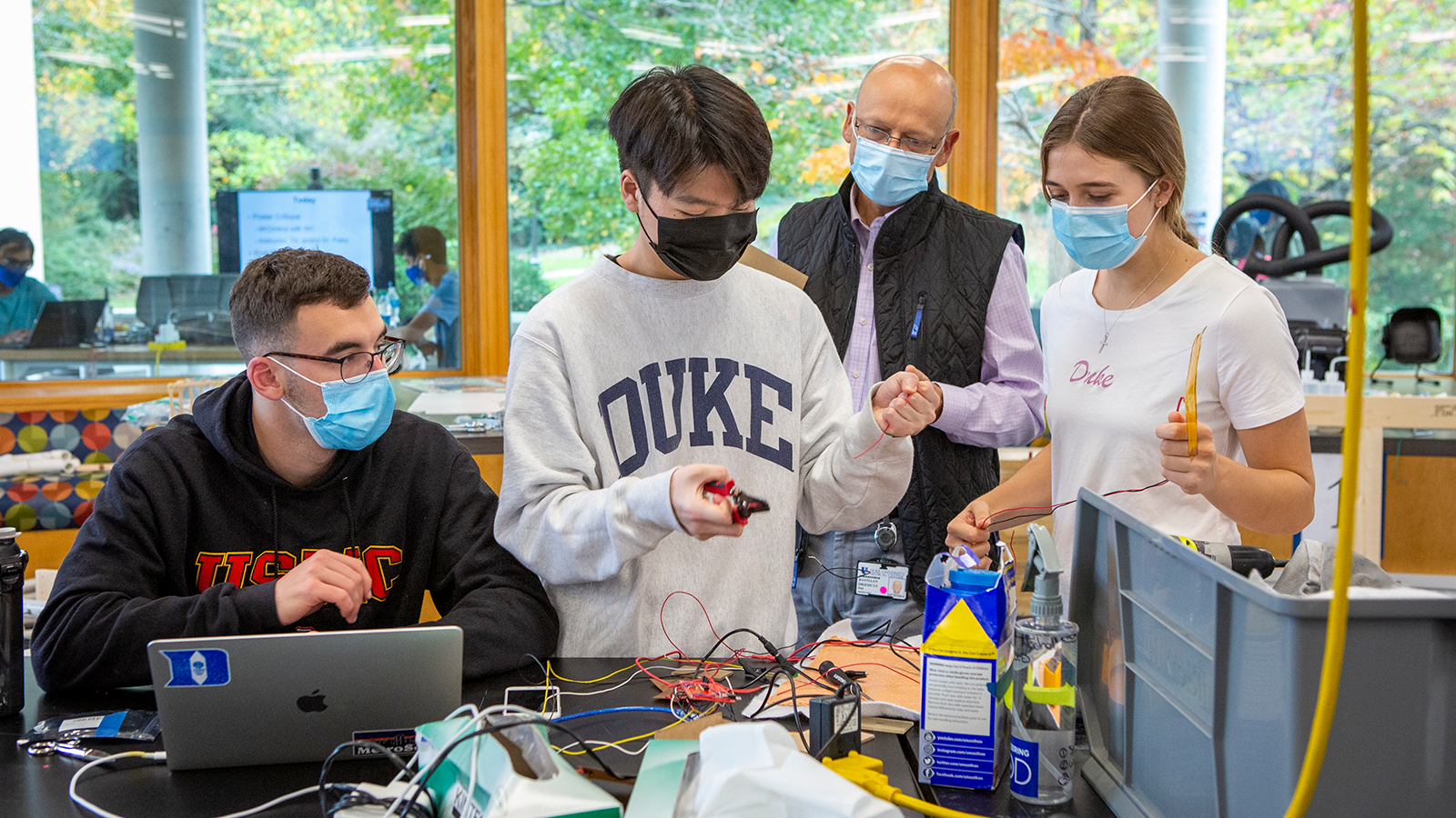 Students working on their engineering design project with a professor.