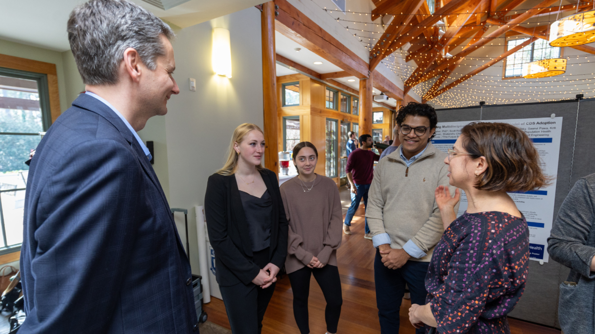 Team members interacting with the director of Duke AI Health at the Duke AI Health Showcase in December 2023.